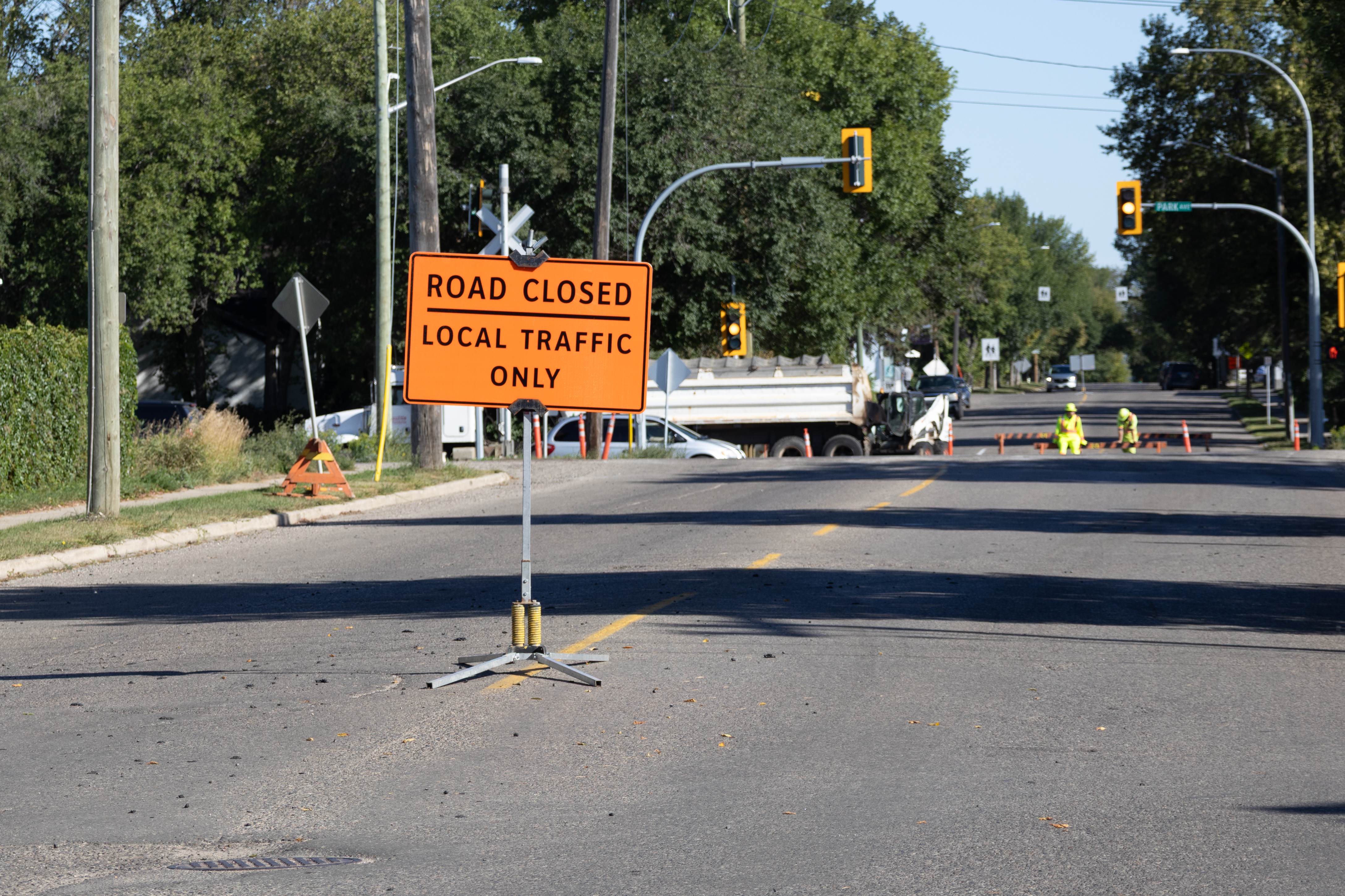 Road Closured sign with a crew doing street repairs in the background