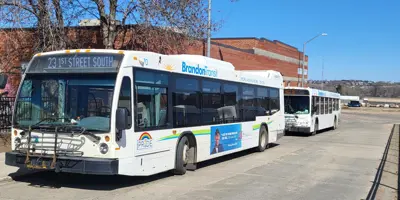 Two buses sitting at the bus terminal downtown