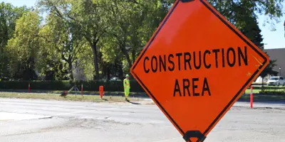 Construction Area sign with a flag person in the background.